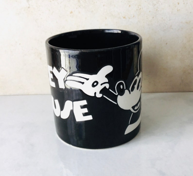 May include: Black ceramic mug with a white image of Mickey Mouse and the text "Disney Mouse" on the side.