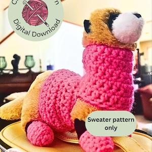 May include: A handmade crochet animal toy with a pink sweater and a tan and brown head. The image includes text that says "Crochet Pattern Digital Download" and "Sweater pattern only". The toy is sitting on a yellow surface.