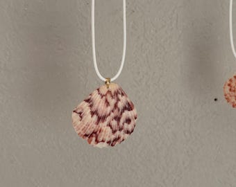 Handmade pendant necklace featuring a seashell on a white cord.