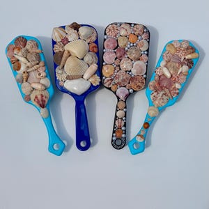 May include: A white ceramic mug with a black handle and the text "But First, Coffee" in a black, handwritten-style font. The mug is on a white surface.