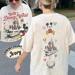 Peut inclure: Un t-shirt ivoire arborant un motif vertical compos&eacute; de Mickey Mouse, d'un ch&acirc;teau, d'un monorail et d'un d&ocirc;me g&eacute;od&eacute;sique, agr&eacute;ment&eacute; de ballons et d'&eacute;toiles color&eacute;s. Le texte Walt Disney World est imprim&eacute; en rouge au-dessus du ch&acirc;teau.