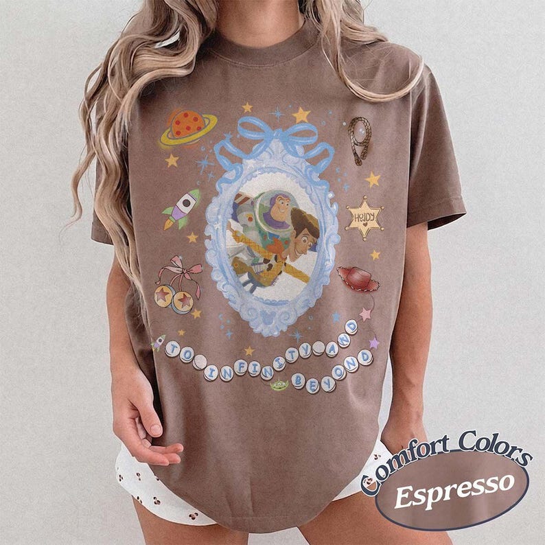 Peut inclure: Un t-shirt marron &agrave; manches courtes avec un cadre bleu clair orn&eacute; au centre contenant Buzz l'&Eacute;clair et Woody. Les graphismes incluent une plan&egrave;te, une fus&eacute;e, une &eacute;toile de sh&eacute;rif avec le texte Howdy, un chapeau et le texte To Infinity and Beyond.