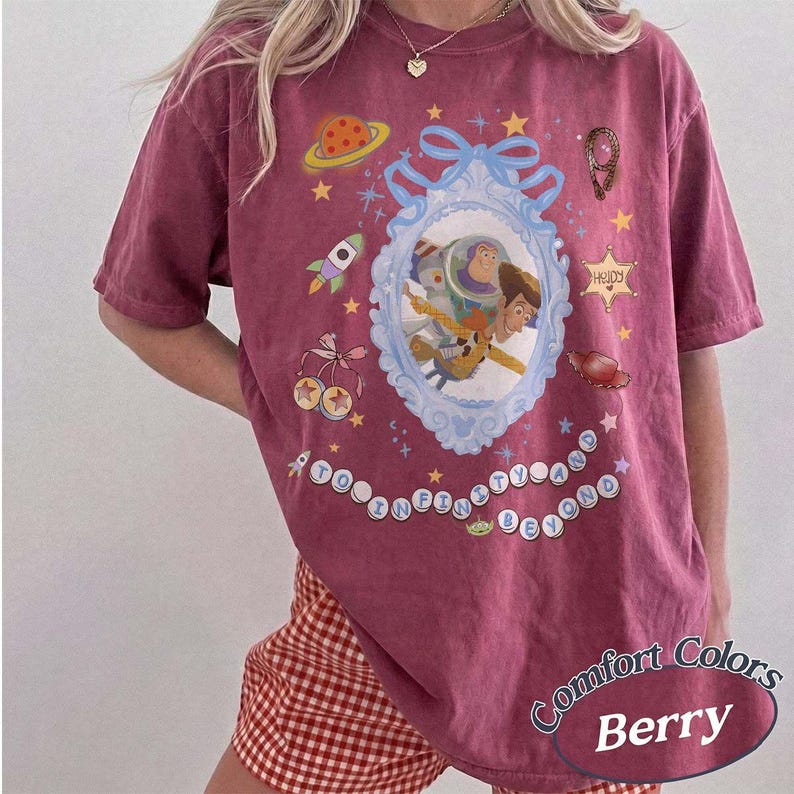 Peut inclure: Un t-shirt &agrave; manches courtes couleur baie avec un cadre orn&eacute; bleu clair central contenant Buzz l'&Eacute;clair et Woody. Les graphismes incluent une plan&egrave;te, une fus&eacute;e, une &eacute;toile de sh&eacute;rif et le texte TO INFINITY AND BEYOND en perles circulaires.