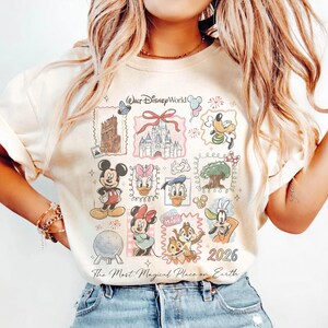 May include: Cream-colored t-shirt featuring a colorful collage of Disney characters and landmarks. The design includes Mickey Mouse, Minnie Mouse, Donald Duck, and Chip and Dale, along with the text "Walt Disney World" and "The Most Magical Place on Earth."
