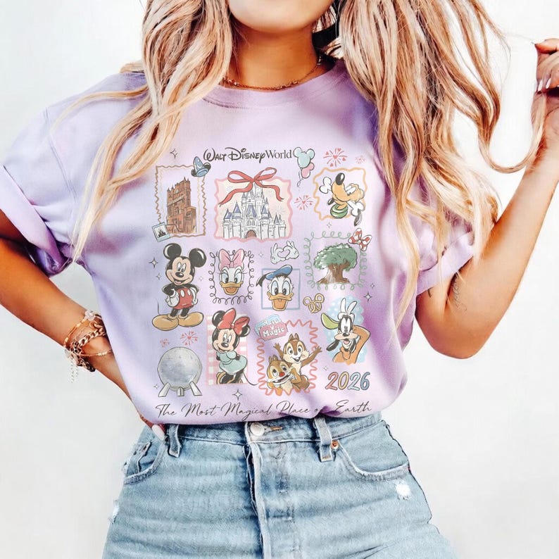 May include: A light purple t-shirt featuring a collage of Disney World images and characters. The design includes Mickey Mouse, Minnie Mouse, Donald Duck, and Goofy, along with the text "Walt Disney World" and "The Most Magical Place on Earth 2026."