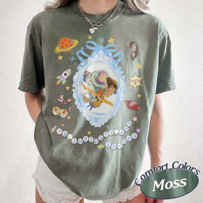 Peut inclure: Un t-shirt &agrave; manches courtes vert mousse avec un cadre orn&eacute; bleu clair central contenant des illustrations de Buzz l'&Eacute;clair et Woody. Autour du cadre se trouvent de petits graphismes d'une plan&egrave;te, d'une fus&eacute;e, d'&eacute;toiles et le texte "To Infinity and Beyond."