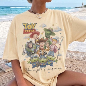 Puede incluir: Una camiseta de manga corta de color amarillo p&aacute;lido con un estampado gr&aacute;fico de los personajes de Toy Story, incluyendo a Woody, Buzz Lightyear, Jessie, Bo Peep, Rex y tres alien&iacute;genas. El texto dice Toy Story y You've got a Friend in me.