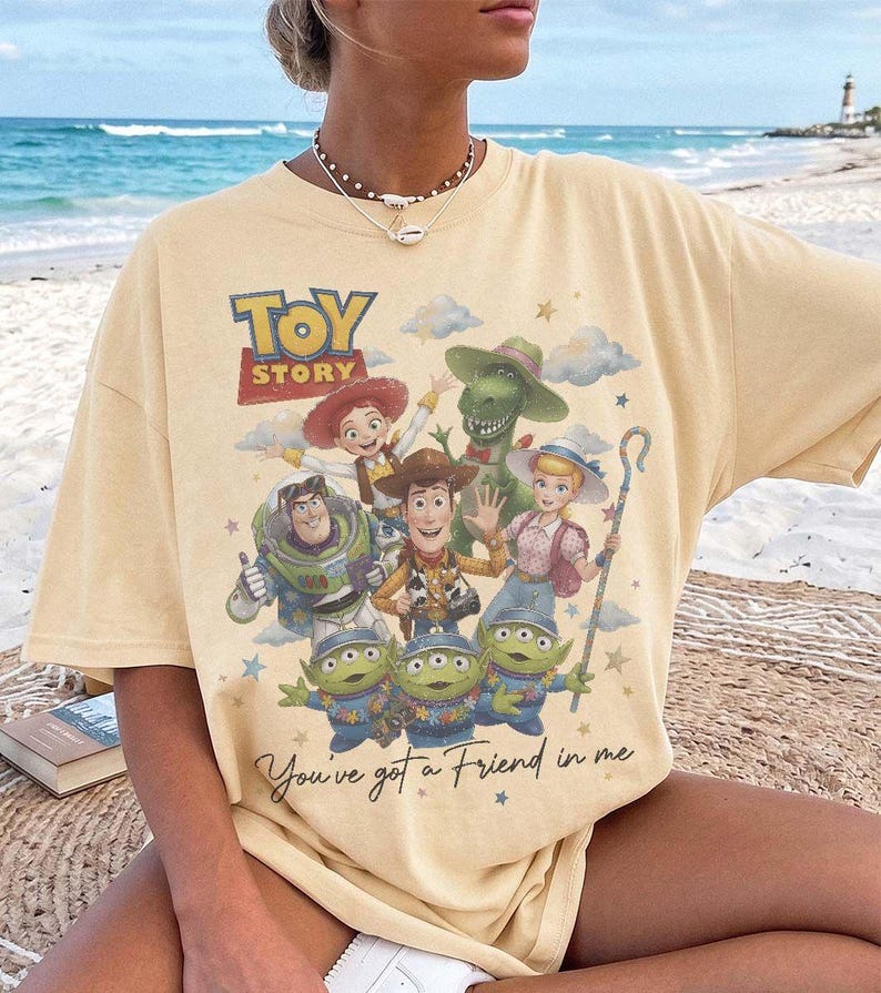 Puede incluir: Una camiseta de manga corta de color amarillo p&aacute;lido con un estampado gr&aacute;fico de los personajes de Toy Story, incluyendo a Woody, Buzz Lightyear, Jessie, Bo Peep, Rex y tres alien&iacute;genas. El texto dice Toy Story y You've got a Friend in me.