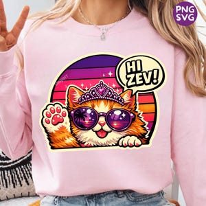 Könnte beinhalten: Hellrosa Sweatshirt mit einem Cartoon-Katzen-Design. Die Katze trägt eine Sonnenbrille, eine Tiara und eine Sprechblase mit der Aufschrift "Hi Zev!". Die Katze ist orange und weiß, mit erhobener Pfote. Der Hintergrund ist ein Sonnenuntergang.