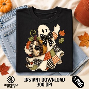 Puede incluir: Una camiseta negra con un gráfico de un fantasma blanco que lleva un lazo de lunares blanco y negro. El fantasma sostiene una calabaza de patchwork con un pequeño icono de gato negro. La parte inferior del cuerpo tiene varios patrones naranjas, verdes y negros.