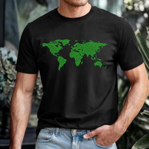 Puede incluir: Camiseta negra de cuello redondo con un diseño de mapa del mundo pixelado en verde. El gráfico representa los continentes y las masas terrestres en un estilo digital. La camiseta está hecha de un material suave.