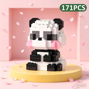May include: A panda bear figure constructed from white, black, and gray building blocks, with pink cheeks. The figure is sitting on a yellow platform, with the text "171PCS" in a green oval. Pink flower petals are scattered around the panda.