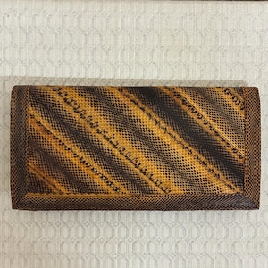 May include: A rectangular clutch bag with a snakeskin pattern in shades of brown and tan. The bag has a dark brown border and a fold-over closure. The snakeskin pattern is arranged in diagonal stripes across the front.