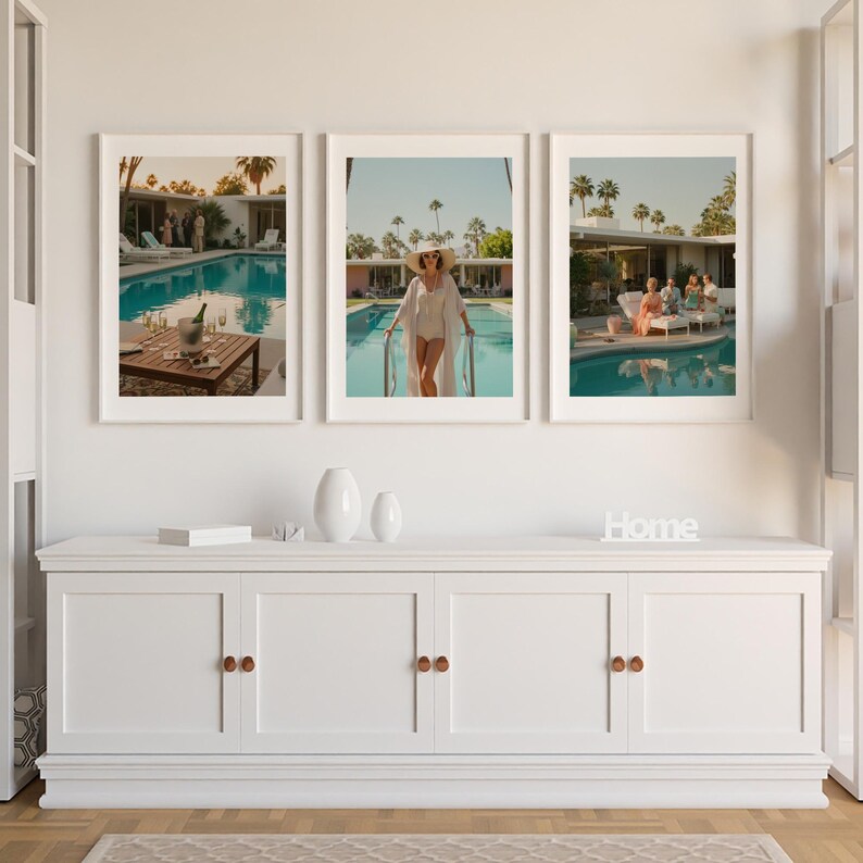 May include: A triptych of framed art prints depicting scenes by a swimming pool. One shows a table with a champagne bottle and glasses, another a person in a pool, and the third, people lounging by the pool. The prints are framed in white.