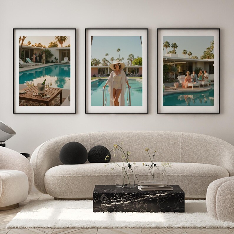 May include: Three framed art prints depicting poolside scenes. One shows a table with champagne, another a person in a white outfit by a pool, and the third, people lounging by a pool. The prints are displayed above a cream-colored sofa.