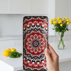 Może przedstawiać: Prostokątna taca ceramiczna z detalicznym, symetrycznym wzorem mandali w odcieniach głębokiej czerwieni, czerni i bieli. Wz&oacute;r składa się z koncentrycznych okręg&oacute;w, misternych płatk&oacute;w kwiatowych oraz geometrycznych kształt&oacute;w pokrywających powierzchnię.