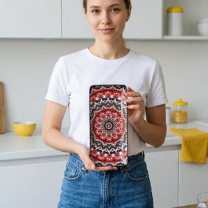 Może przedstawiać: Prostokątna taca ceramiczna z wyrazistym wzorem mandali w kolorach czerwonym, czarnym i białym. Projekt składa się ze złożonych kształt&oacute;w geometrycznych i motyw&oacute;w kwiatowych ułożonych w symetryczny, powtarzający się okrągły układ na powierzchni.