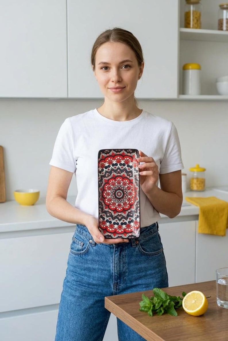 Może przedstawiać: Prostokątna taca ceramiczna z wyrazistym wzorem mandali w kolorach czerwonym, czarnym i białym. Projekt składa się ze złożonych kształt&oacute;w geometrycznych i motyw&oacute;w kwiatowych ułożonych w symetryczny, powtarzający się okrągły układ na powierzchni.