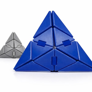 May include: Two geometric pyramid puzzles. The larger one is a vibrant blue, while the smaller one in the background is a metallic gray. Each pyramid is constructed from interlocking triangular pieces, creating a three-dimensional puzzle.