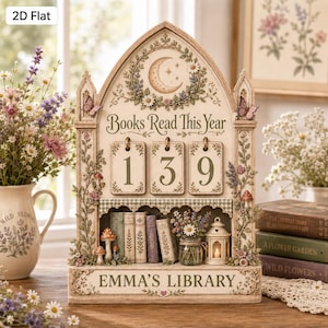 May include: A decorative tabletop book tracker featuring a pointed arch frame with floral and crescent moon motifs. It displays the text 'Books Read This Year' above three hanging number tiles showing 139, and 'EMMA'S LIBRARY' at the base.