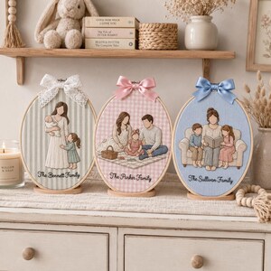 Puede incluir: Tres bastidores de bordado ovalados con retratos familiares personalizados sobre tela. El primero muestra a un progenitor con dos hijos, el segundo a una familia de tres en un picnic y el tercero a un progenitor leyendo a dos ni&ntilde;os.
