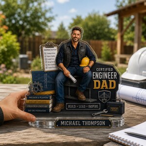 Può includere: Un regalo personalizzato in acrilico per un papà ingegnere. Il design presenta un uomo con un casco, dei progetti e il testo "Certified Engineer Dad". Include il nome "Michael Thompson" e le frasi "Build, Lead, Inspire".