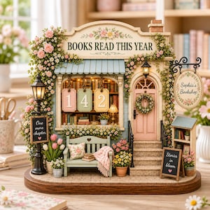 May include: A miniature bookstore model titled Books Read This Year with a pink door, a green bench, and hanging signs reading One more chapter and Stories in bloom. The facade features floral vines, a street lamp, and a counter showing 142.