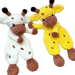 May include: Two plush giraffe toys made of soft, textured yarn. One giraffe is primarily white with brown spots and brown hooves, while the other is bright yellow with brown spots and brown hooves. Both feature small black eyes and brown horns.