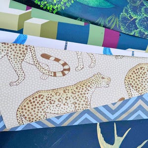 May include: A collection of patterned papers, featuring designs such as a cheetah print, geometric shapes, and botanical illustrations. Colors include green, blue, brown, and white. The papers are layered, showcasing a variety of textures and patterns.