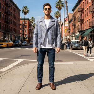 May include: A light blue snakeskin-patterned leather jacket with a white t-shirt and dark blue jeans. The jacket has a classic biker style with an asymmetrical zipper and a notched lapel. Brown leather boots complete the look.