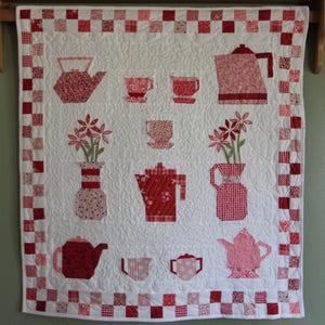May include: A white quilt with a red and white checkered border. The quilt features a variety of red and white teapots, cups, and flowers.