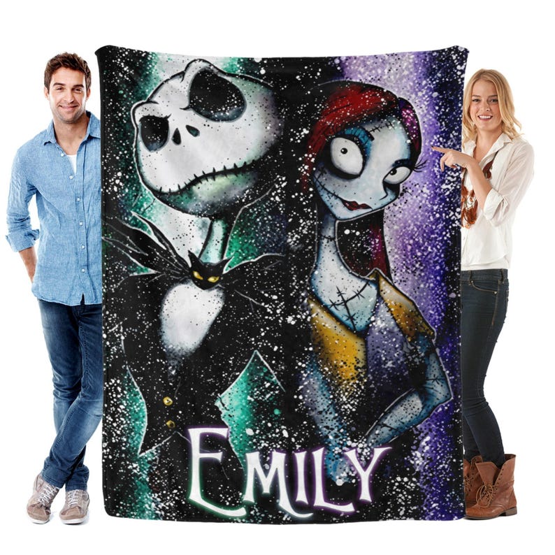 Peut inclure: Une grande couverture rectangulaire repr&eacute;sentant Jack Skellington et Sally de L'&Eacute;trange No&euml;l de Monsieur Jack. La couverture a un fond sombre avec des effets d'&eacute;claboussures blanches et le nom "EMILY" en &eacute;criture blanche. Jack est en costume noir, et Sally a les cheveux roux.