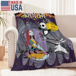May include: A plush throw blanket featuring a scene from The Nightmare Before Christmas. The design includes Jack Skellington offering a rose to Sally, with Zero nearby. The blanket has a purple border and the word "SARAH" is at the top.