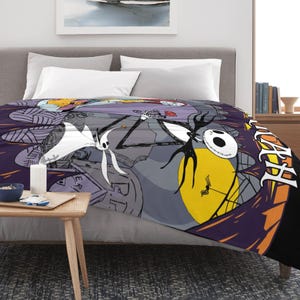 May include: A patterned blanket featuring characters from The Nightmare Before Christmas. The design includes Jack Skellington, Sally, and other characters against a purple and gray background. The blanket has a black border and is draped over a bed.