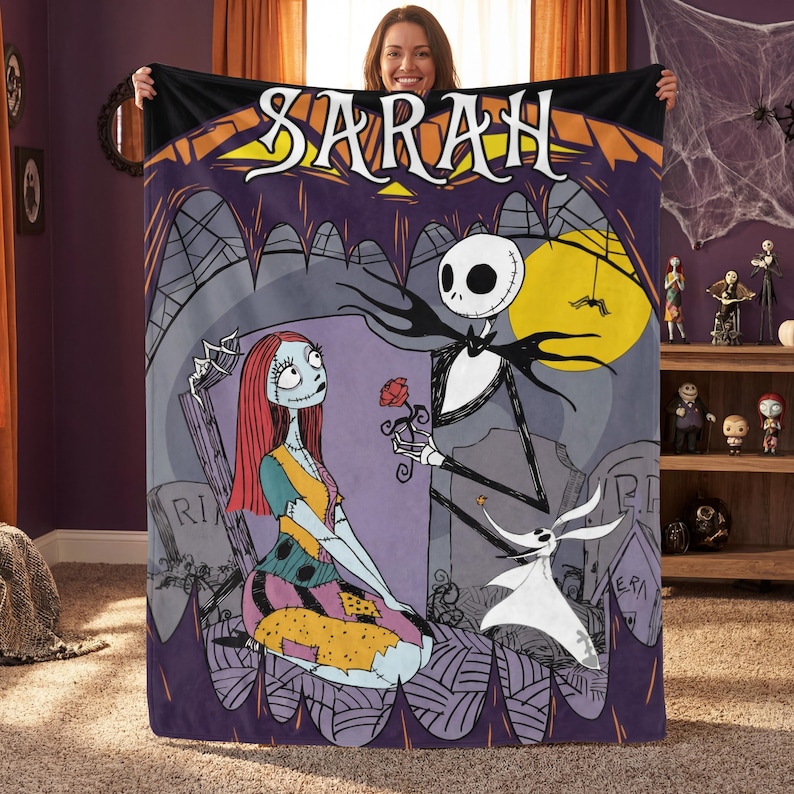 May include: A purple and black throw blanket featuring a scene from The Nightmare Before Christmas. The blanket depicts Jack Skellington offering a rose to Sally, with Zero the ghost dog nearby. The name "SARAH" is displayed across the top.
