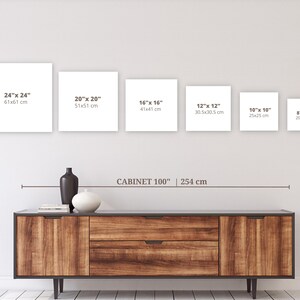May include: A wooden cabinet with a dark top and two drawers, holding decorative vases. Above, six white square canvases are displayed, ranging in size from 8" x 8" to 24" x 24". The text "CABINET 100" is visible.