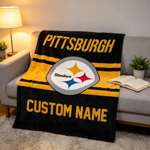 May include: A black and yellow fleece blanket featuring the Pittsburgh Steelers logo in the center. The word PITTSBURGH is printed in large yellow letters at the top, and the words CUSTOM NAME are printed in yellow letters at the bottom.