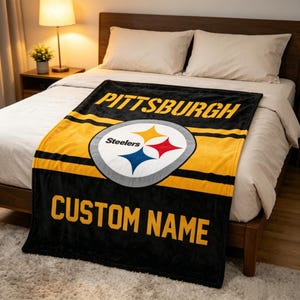 May include: A black and yellow fleece blanket featuring the Pittsburgh Steelers logo in the center, the word PITTSBURGH in yellow text at the top, and the placeholder text CUSTOM NAME in yellow block letters at the bottom of the blanket.