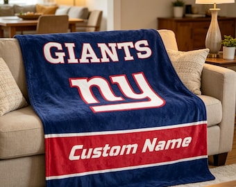 Może przedstawiać: Pluszowy granatowy koc z białym napisem GIANTS nad dużym białym logo NY z czerwoną obwódką. Szeroki czerwony poziomy pasek biegnie wzdłuż dolnej części, z białym napisem Custom Name wyśrodkowanym wewnątrz paska.