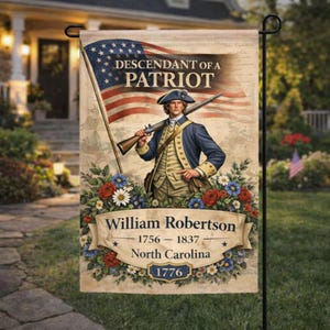 May include: A garden flag featuring a patriotic design with an illustration of a man in colonial attire holding a rifle, with the American flag in the background. The flag reads "Descendant of a Patriot" and "William Robertson 1756-1837 North Carolina 1776".