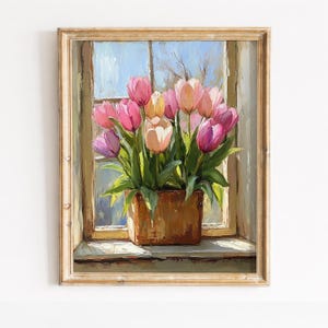 May include: A framed painting of a bouquet of tulips in a wooden planter on a windowsill. The tulips are various shades of pink and peach, with green leaves. The window shows a blue sky and tree branches. The frame is a light, warm color.