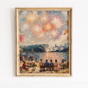 May include: A framed vintage painting showing a fireworks display over a lake. The artwork features a vibrant sky filled with bursts of red, orange, and yellow fireworks. People are gathered on the shore, enjoying the spectacle. An American flag is visible.