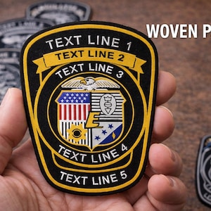 May include: A black and yellow woven patch with the text "TEXT LINE 1", "TEXT LINE 2", "TEXT LINE 3", "TEXT LINE 4", and "TEXT LINE 5". The patch has a shield design with an eagle and a flag.