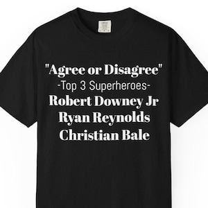 A black t-shirt with white text that reads "Agree or Disagree" and "Top 3 Superheroes" along with the names "Robert Downey Jr", "Ryan Reynolds", and "Christian Bale".
