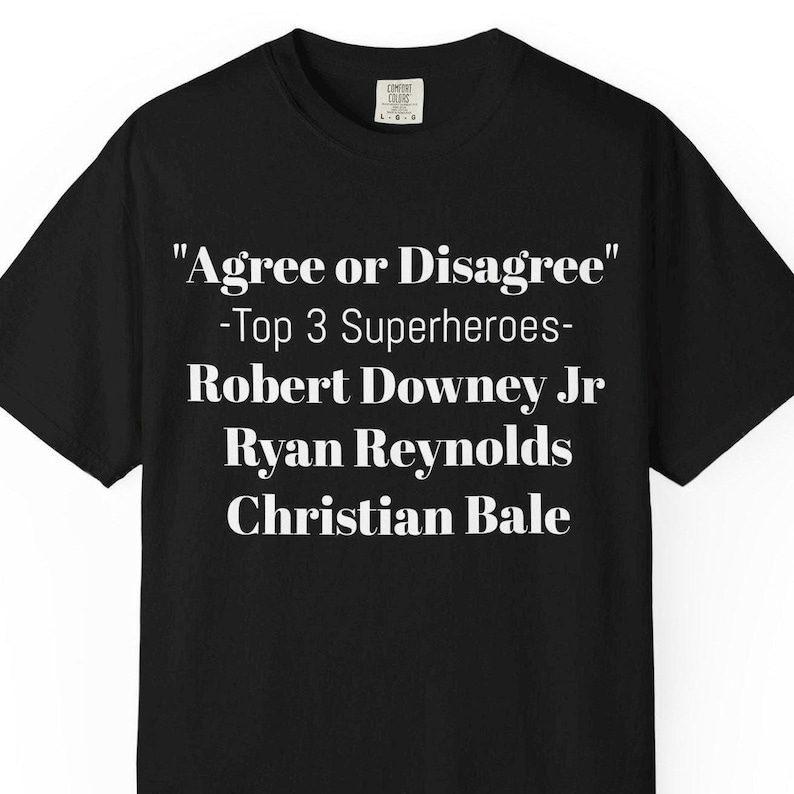 A black t-shirt with white text that reads "Agree or Disagree" and "Top 3 Superheroes" along with the names "Robert Downey Jr", "Ryan Reynolds", and "Christian Bale".