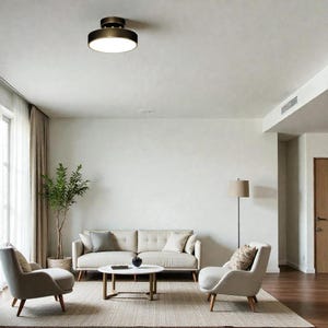 May include: A contemporary living room featuring a beige sofa, armchairs, and a round coffee table on a rug. A bronze ceiling light provides illumination. A floor lamp and a potted plant enhance the decor, creating a comfortable atmosphere.