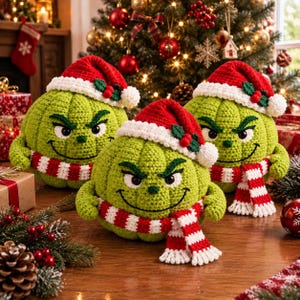 May include: Three round, green, crocheted plush figures with grumpy facial expressions, each wearing a red and white Santa hat with a holly accent and a matching red and white striped scarf. The figures have textured yarn surfaces.
