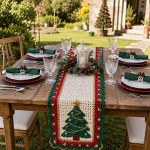 May include: A rectangular crochet table runner featuring a central cream-colored panel with a green Christmas tree motif, bordered by red and green scalloped edges adorned with small white beads, set on a wooden table with place settings.