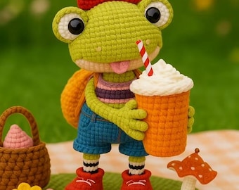 May include: A crocheted frog doll with a red bow, holding an orange drink with whipped cream and a striped straw. The frog wears blue shorts, a striped shirt, and red shoes. A small basket, flowers, and a mushroom are also present.