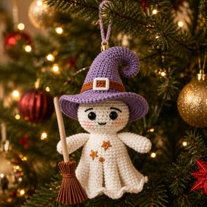 May include: A crocheted ghost ornament wearing a purple pointed hat with a brown band and white buckle. The white ghost figure has black eyes, a small mouth, pink cheeks, and three small orange stars on its body, holding a brown broomstick.